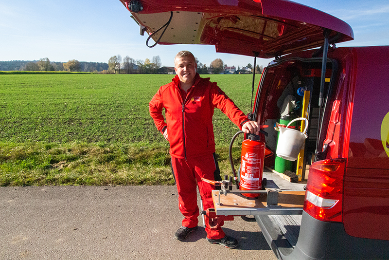 Unbenannt-1 Techniker mit Feuerlöscher am geöffneten Firmenwagen