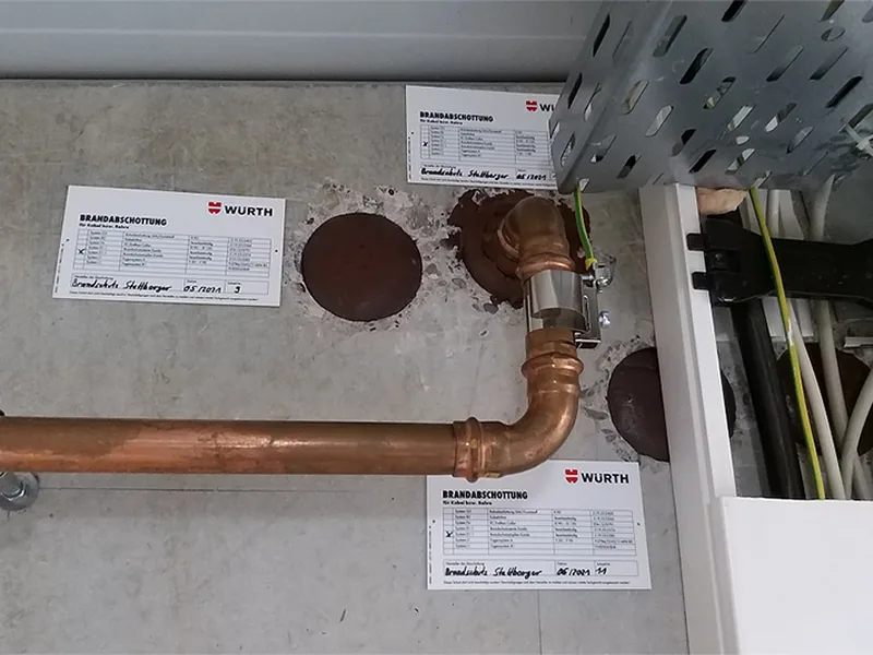 Abgeschottete Leitungsdurchführungen in einer Wand mit Kennzeichnungsschildern