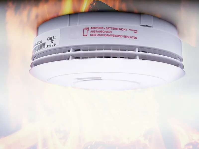 Rauchmelder an der Decke, darunter Flammen